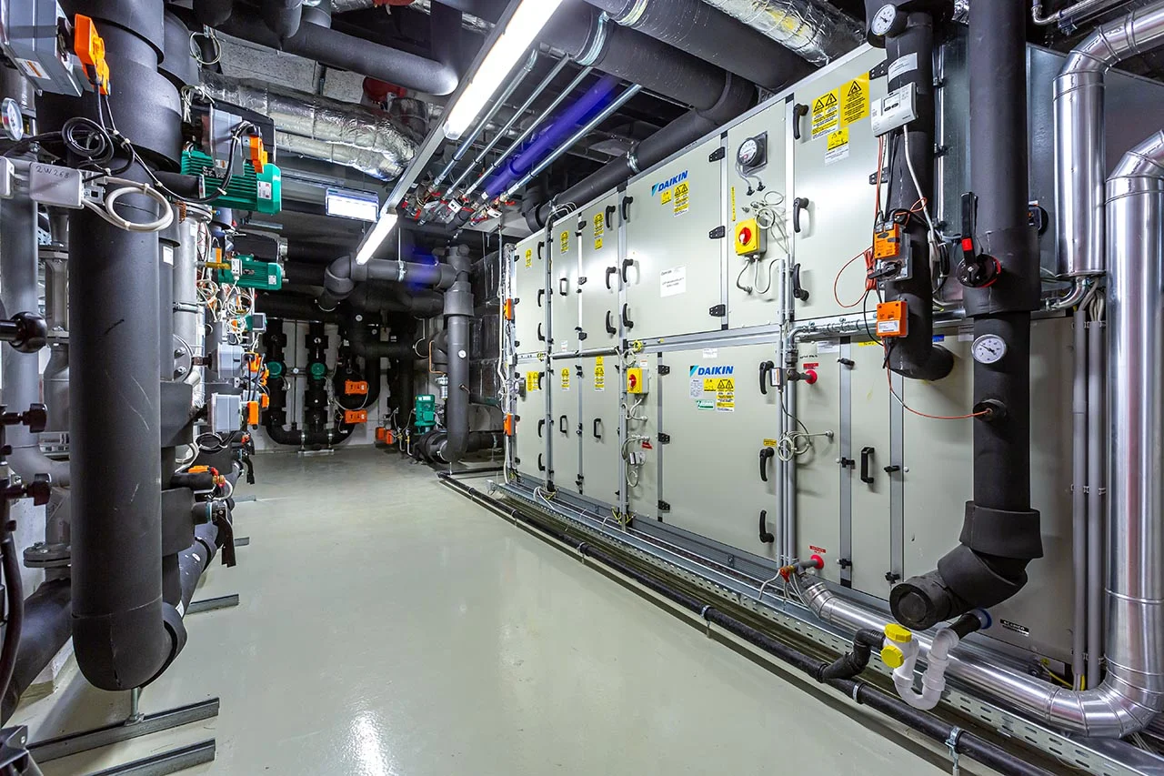 Commercial air handling units and overhead pipework in a mechanical plant room